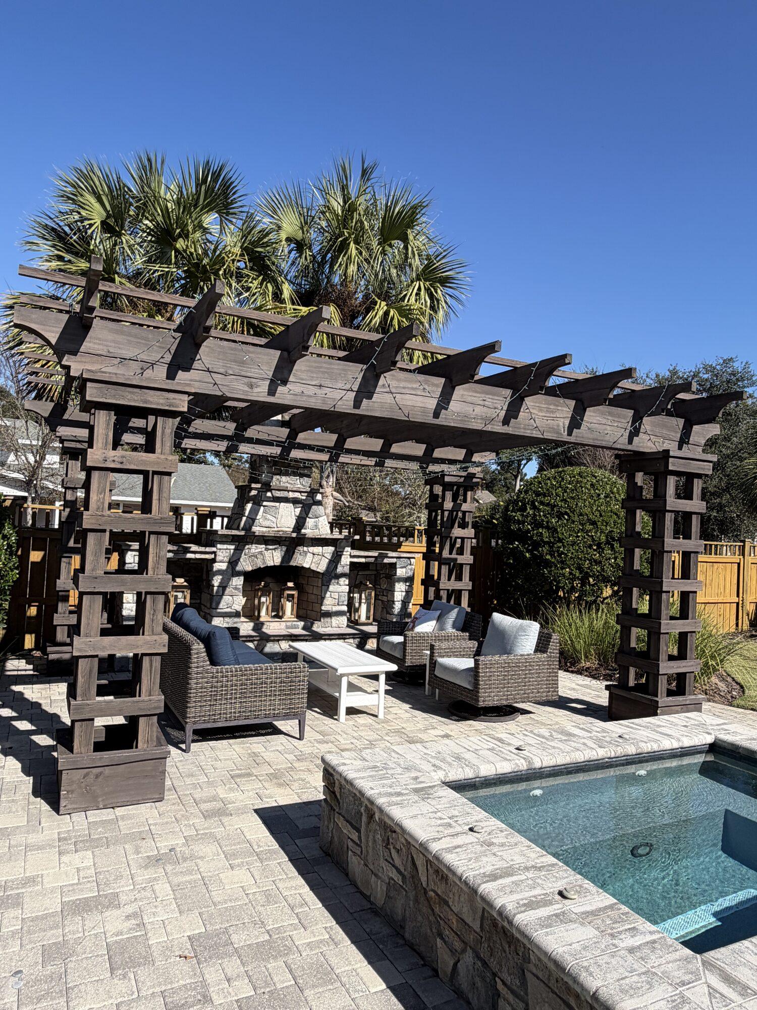 A finished outdoor living space with stone fireplace and pergola